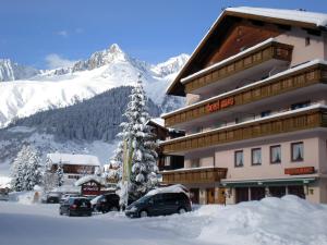 un edificio cubierto de nieve con un árbol de Navidad cubierto de nieve en Hotel Mira, en Sedrun