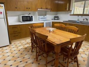 a kitchen with a wooden table and wooden chairs at Stay @ Ray's in West Wyalong