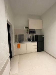 uma cozinha com um frigorífico preto e armários brancos em Monde Residence H12 Batam Centre em Sengkuang