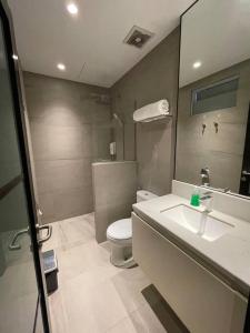 a bathroom with a toilet and a sink and a mirror at Monde Residence H12 Batam Centre in Sengkuang