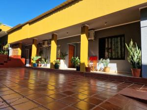 a yellow building with potted plants on a tile floor at Pacurí - Habitaciones Privadas in Puerto Iguazú