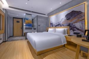 a bedroom with a large white bed and a desk at Tuke China Hotel -Wenzhou South Bus Terminal in Wenzhou