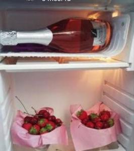 uma garrafa de vinho e dois cestos de morangos num frigorífico em Max B&B Fiera em Bari