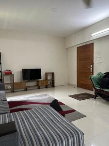 una sala de estar con TV y sofá y una habitación con sofá en GreyRooms en Dhaka