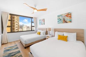 two beds in a room with a large window at Gorgeous Condo with Ocean View, Near Beach, Free Parking in Honolulu
