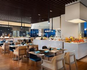 a restaurant with tables and chairs and a kitchen at Le Meridien Hangzhou, Binjiang in Hangzhou