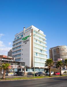 a tall white building with palm trees in front of it at Wyndham Garden Antofagasta Pettra in Antofagasta
