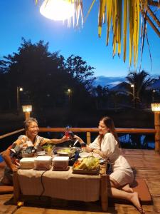two women sitting at a table with food at สวนเกษตรรักษ์ไผ่ Bamboo Conservation Farm in Surin