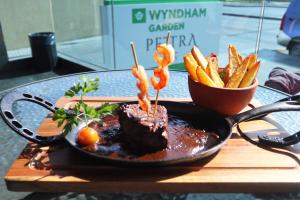 eine Pfanne mit Fleisch und Pommes Frites auf dem Tisch in der Unterkunft Wyndham Garden Antofagasta Pettra in Antofagasta