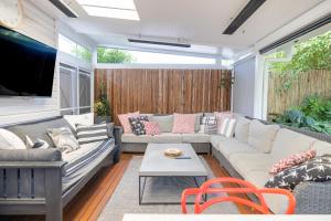 a living room with couches and a tv at Barbara's Guesthouse in Byron Bay