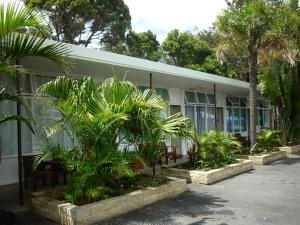 a building with palm trees in front of it at Hoey Moey Backpackers in Coffs Harbour