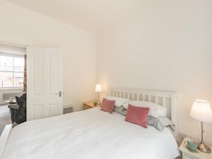 biała sypialnia z białym łóżkiem z czerwonymi poduszkami w obiekcie Clifton Apartment - Uk42845 w mieście Lytham St Annes