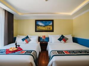 a hotel room with two beds and a picture on the wall at Ladybird Sapa Hotel in Sa Pa