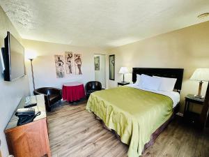 a hotel room with a bed and two chairs at Sage N Sand Motel in Moses Lake