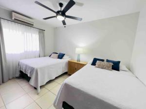 sypialnia z 2 łóżkami i wentylatorem sufitowym w obiekcie Hermosa villa en Palma Real w mieście La Ceiba