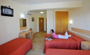 Eine Frau auf einem Bett in einem Hotelzimmer in der Unterkunft Dom Fernando II in Loulé
