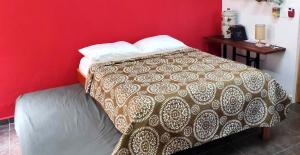 Bett in einem Zimmer mit roter Wand in der Unterkunft Habitacion Roja / Casa del Café in Campeche