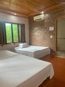 um quarto com duas camas e uma parede de tijolos em Nhà hàng-Khách sạn Hồ Núi Đính em Ninh Binh