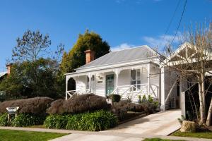 a white house with a porch and landscaping at Ravenswood in Daylesford