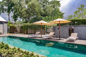 a swimming pool with two umbrellas and two chairs at Tao Resort and Villas (SHA Extra+) in Phuket Town