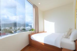 a bedroom with a white bed and a large window at The Backpacker Hostel and spa in Da Nang