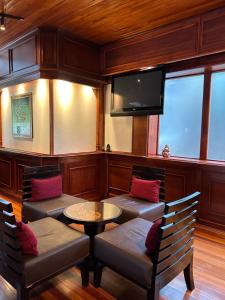 モンテベルデ・コスタリカにあるTrapp Family Lodge Monteverdeの椅子2脚、テーブル、テレビが備わる客室です。