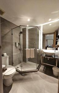y baño con ducha, aseo y lavamanos. en The Brunei Hotel, en Bandar Seri Begawan
