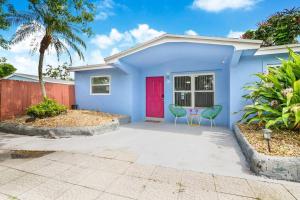 een blauw huis met een rode deur en twee stoelen bij Pretty in Pink - Pool - Vanity Area - Coffee Nook in Fort Lauderdale