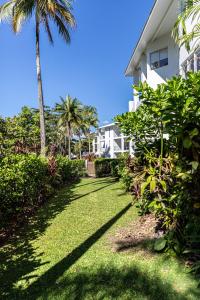 un césped frente a una casa con palmeras en Beaches Holiday Apartments with Onsite Reception & Check In en Port Douglas