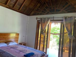 um quarto com uma cama e uma porta de vidro deslizante em Hotel La Costa Salango em Puerto López