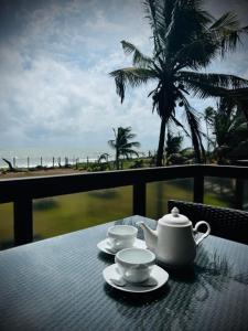 uma mesa com chávenas e bules sentados numa varanda em Driftwood Villa em Pamunugama