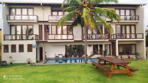 a building with a palm tree and a picnic table at Driftwood Villa in Pamunugama