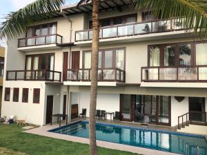 an apartment building with a swimming pool and a palm tree at Driftwood Villa in Pamunugama