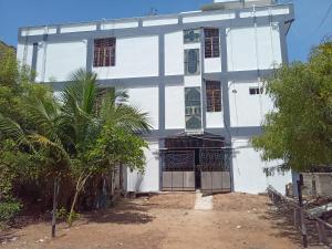 un edificio blanco con una palmera delante en Royal Rasool Residency, en Paramagudi