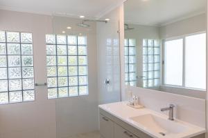 a bathroom with a sink and a shower and a mirror at Beaches Holiday Apartments with Onsite Reception & Check In in Port Douglas