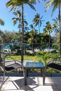 d'une table et de chaises sur un balcon avec des palmiers. dans l'établissement Beaches Holiday Apartments with Onsite Reception & Check In, à Port Douglas