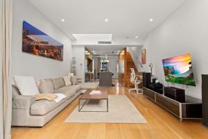 een woonkamer met een bank en een tv bij Modern, Elegant Oasis - Trendy Area - Free Parking in Sydney