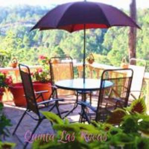 a table and chairs with an umbrella on a patio at TinyHouse La Roca-Cabaña de montaña in Valle de Ángeles