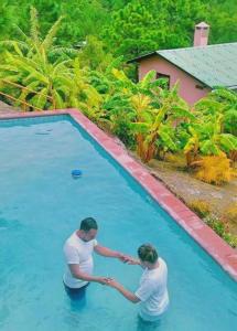 two people are shaking hands near a swimming pool at TinyHouse La Roca-Cabaña de montaña in Valle de Ángeles