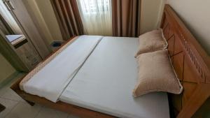 a bed with a wooden headboard with a pillow on it at Star Max Apartments in Kigali