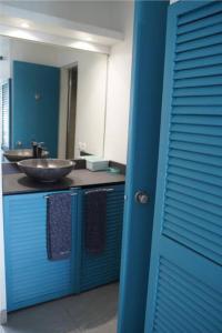 ein blaues Badezimmer mit einem Waschbecken und einem Spiegel in der Unterkunft Rêve bleu au Diamant in Le Diamant
