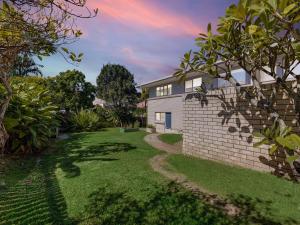 a house with a yard with a brick wall at 25 Oleander Avenue Shelly Beach QLD in Caloundra +4 photos