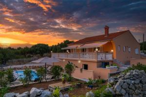 a house with a swimming pool and a sunset at Villa Akulica in Jakišnica
