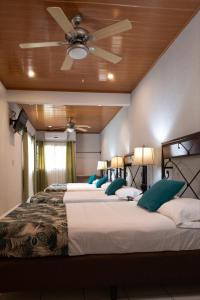 two beds in a room with a ceiling fan at Hotel San Jose Matagalpa in Matagalpa