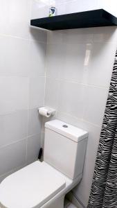 a white bathroom with a toilet and a black shelf at Cozy condo for rent in Davao City +10 photos