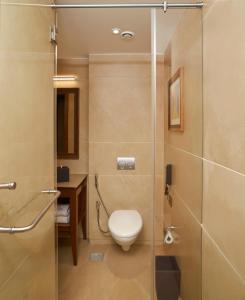 a bathroom with a toilet and a glass shower at Marquis Beach Resort in Candolim