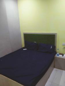 1 cama con sábana azul y pared verde en OYO Hotel Panchtara, en Bhiwāni