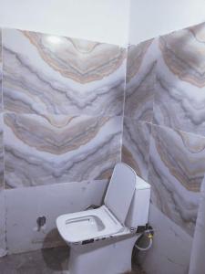 aseo blanco en un baño con pared de mármol en OYO Hotel Panchtara, en Bhiwāni