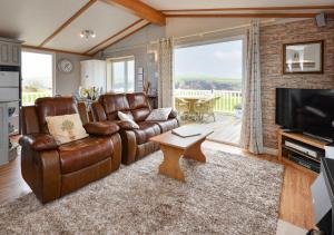 uma sala de estar com um sofá de couro e uma televisão em Lazy Nook em Dinas