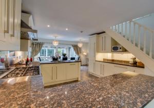 a large kitchen with white cabinets and a staircase at La Villa in Rottingdean